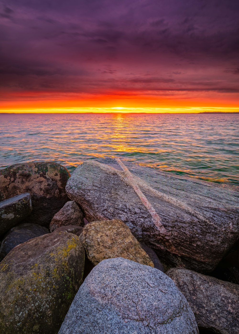 Rocas grises y negras cerca del cuerpo de agua durante la puesta del sol