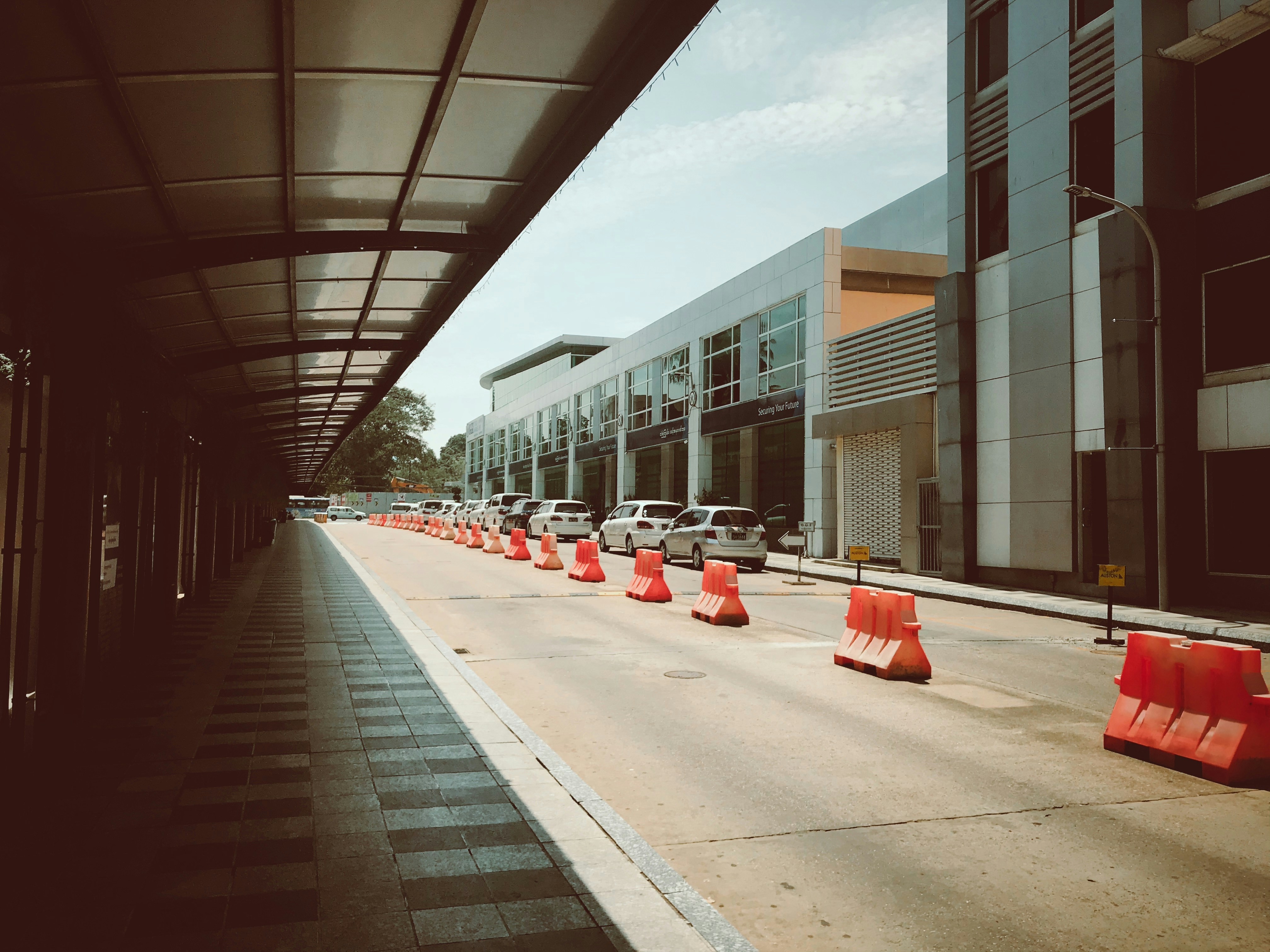 red plastic trash bin on sidewalk during daytime