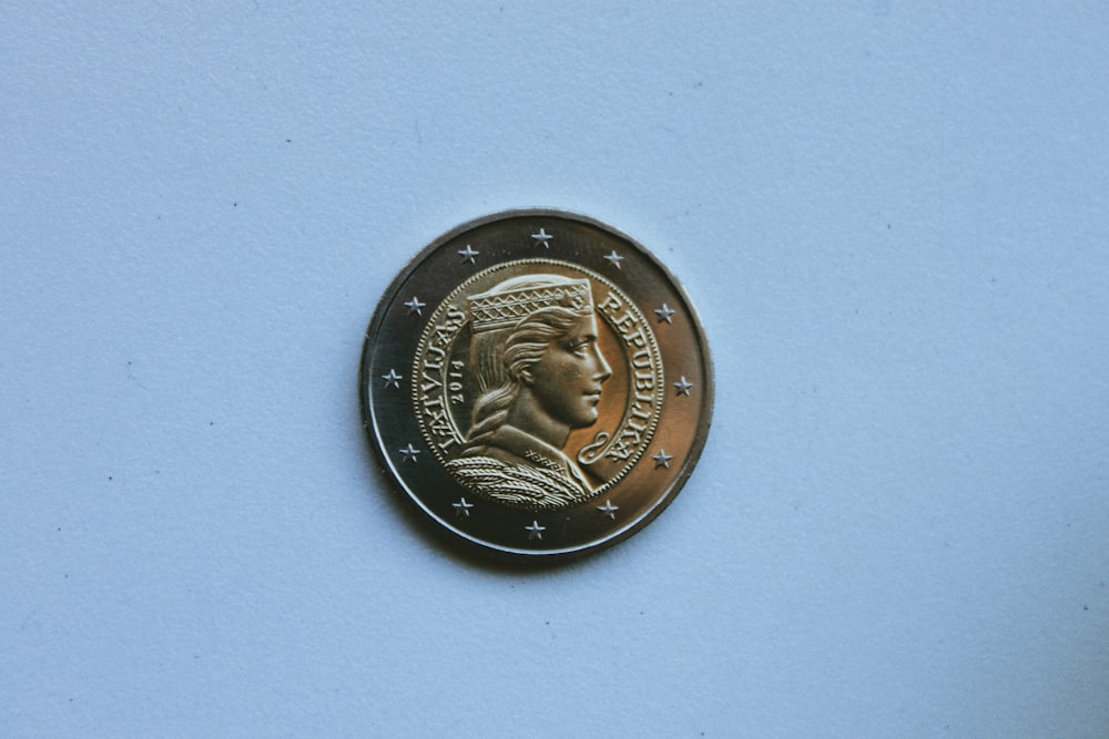 silver round coin on white surface