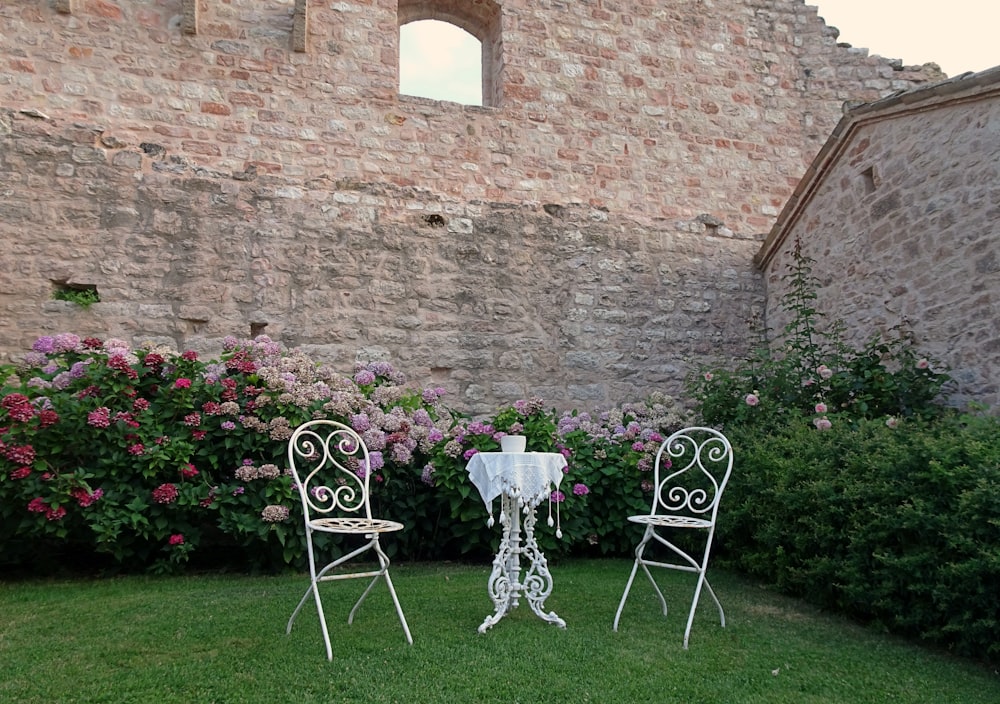 white metal chairs and table near brown brick wall