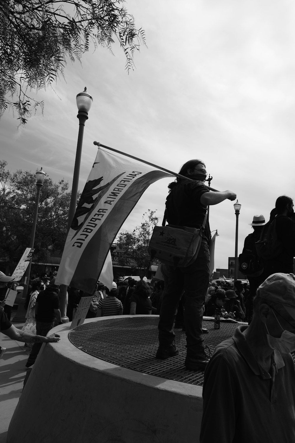 grayscale photo of man in black jacket and pants holding flag