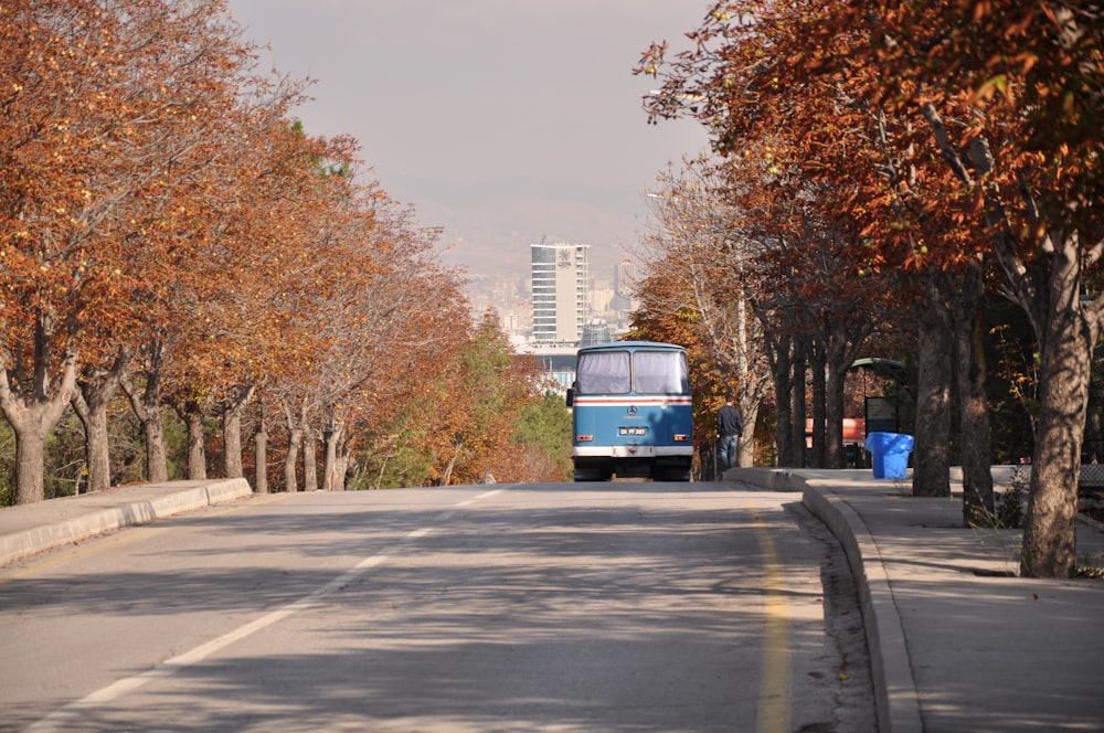 blauer Bus tagsüber auf der Straße in der Nähe von Bäumen