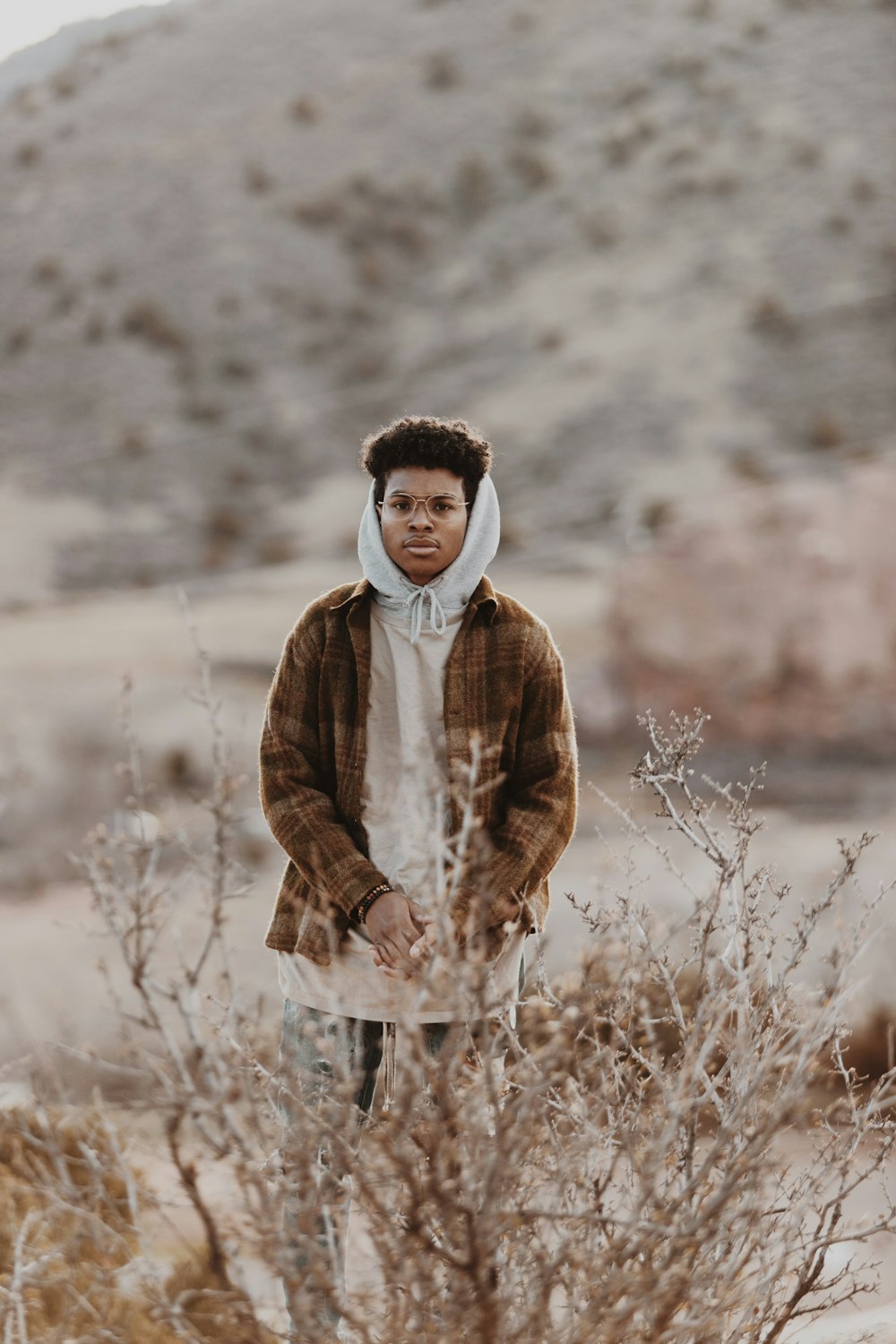 boy in brown and white coat standing on brown grass field during daytime