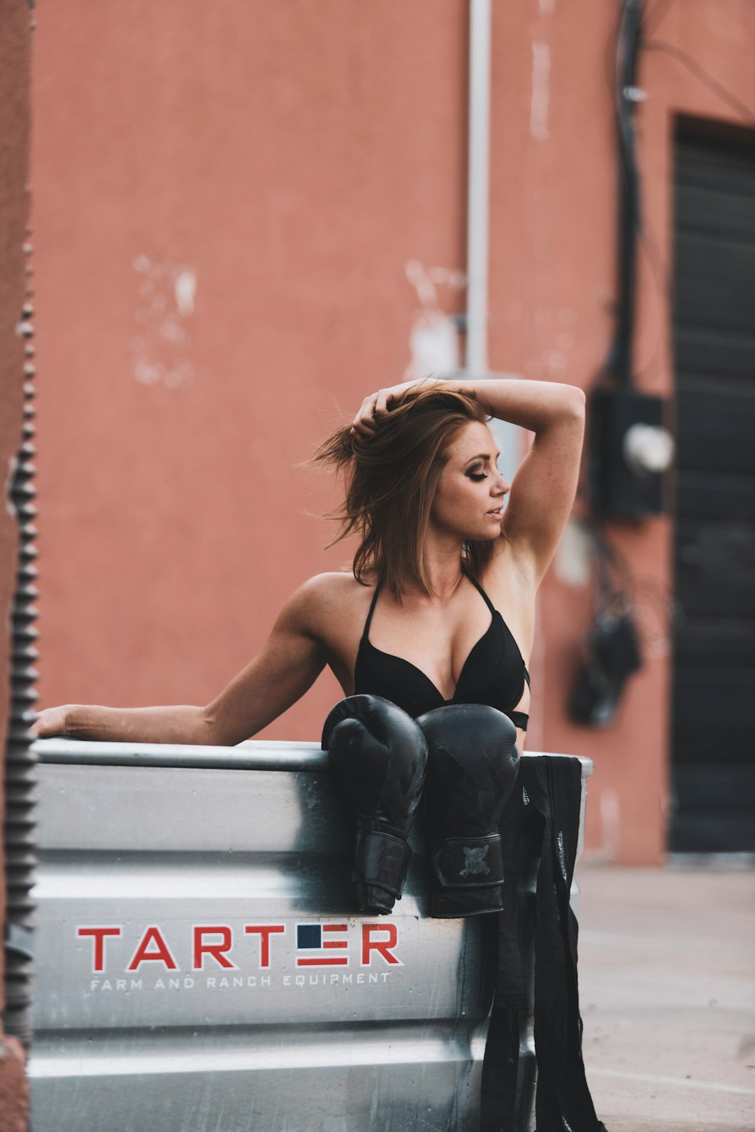 woman in black brassiere and black denim jeans sitting on white wooden bench