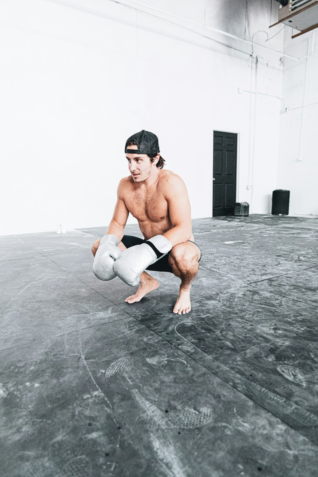 topless man in white shorts kneeling on floor