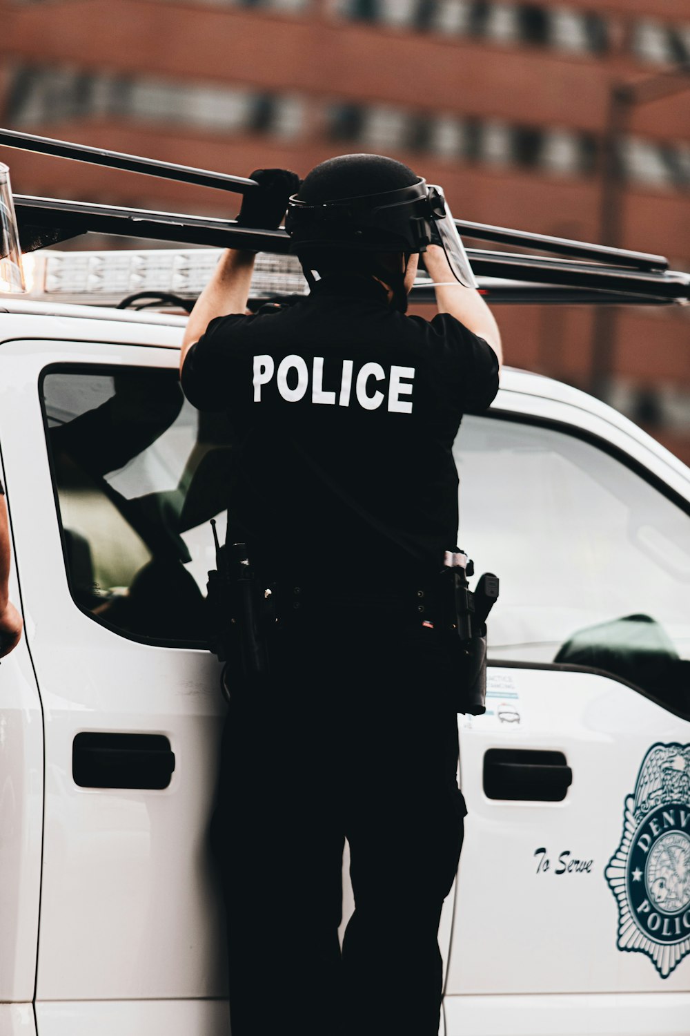 man in black and white police uniform standing beside white car during daytime