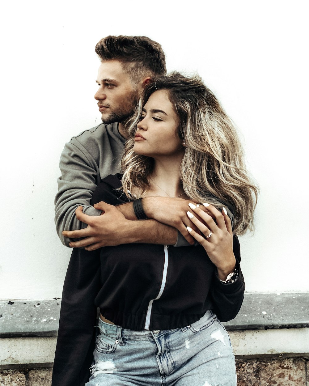 man in gray jacket hugging woman in gray jacket