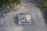 A stencil-style artwork is painted on a concrete surface, featuring a person's face and the text 'I'm kind of a big deal'. Surrounding the artwork, there are patches of grass, small rocks, and more concrete.