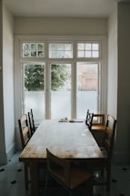 A cozy wooden dining table with chairs in natural light.