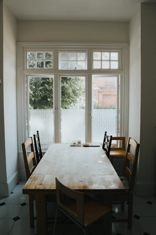 A sturdy wooden dining table with matching chairs, bathed in warm natural light.