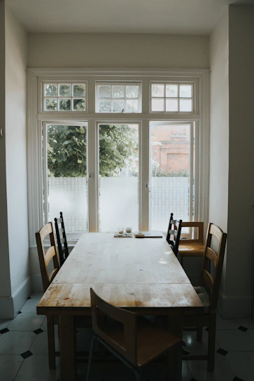 A rustic wooden dining table set in a cozy kitchen with natural light streaming through the window.