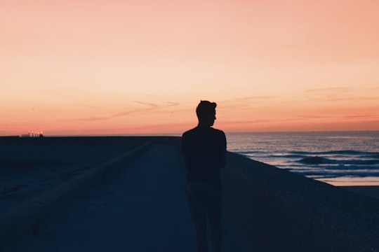 silhouette of person standing on seashore during sunset in Dunkerque France