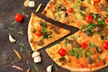 pizza with tomato and green leaves on white ceramic plate