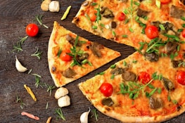 pizza with tomato and green leaves on white ceramic plate