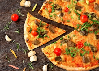 pizza with tomato and green leaves on white ceramic plate