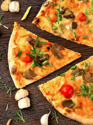 pizza with tomato and green leaves on white ceramic plate