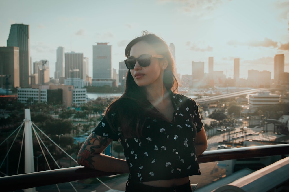 woman in black and white floral shirt and blue denim daisy dukes leaning on brown wooden