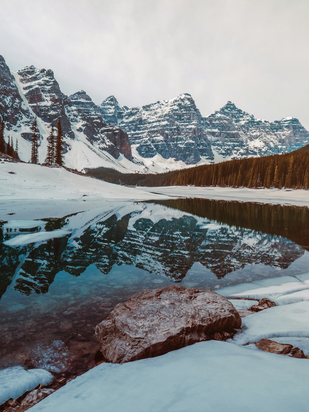 snow covered mountain near lake during daytime