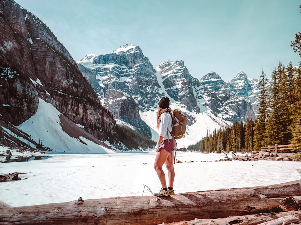 woman in white shirt and blue denim shorts standing on snow covered ground during daytime