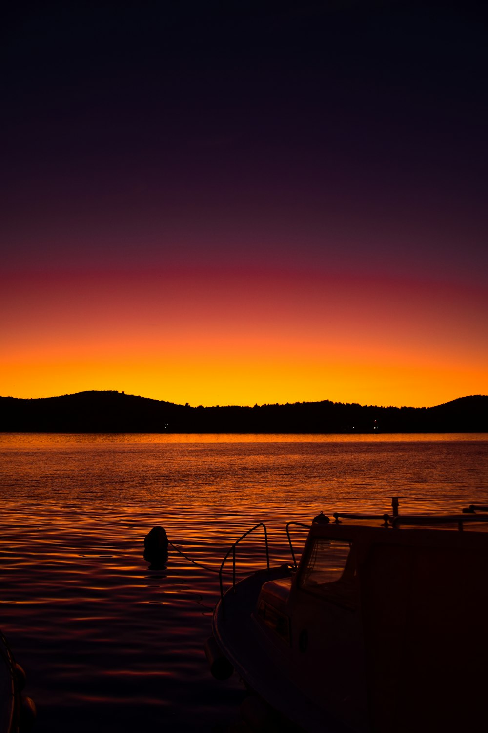 silhouette of person sitting on bench near body of water during sunset