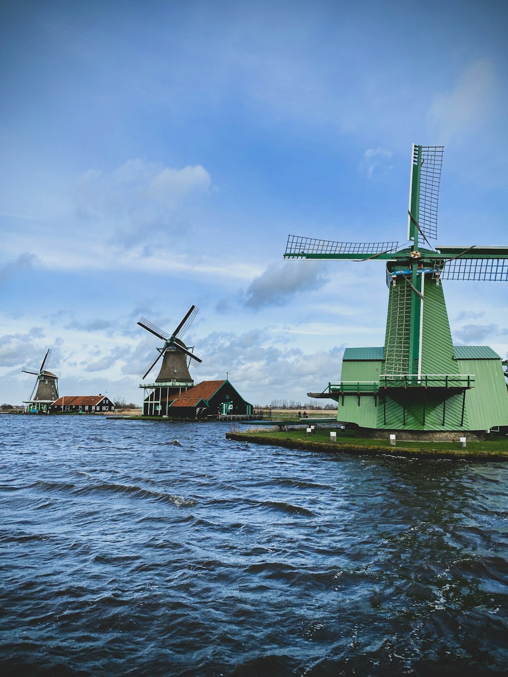 moinho de vento verde perto do corpo de água durante o dia