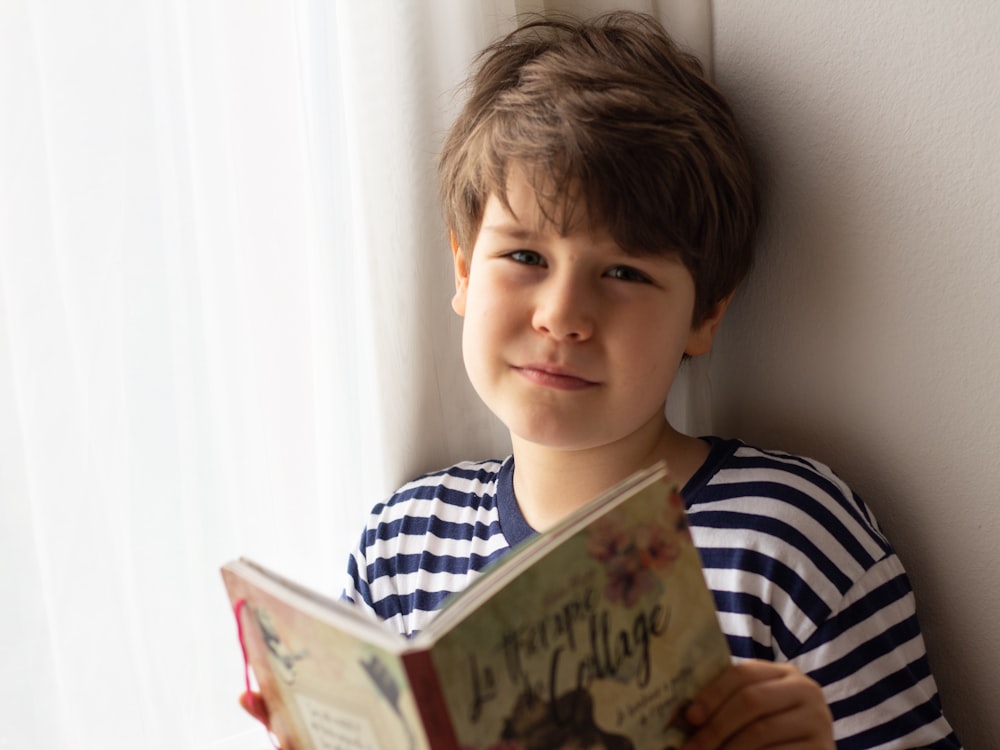 boy in black and white striped shirt holding book
