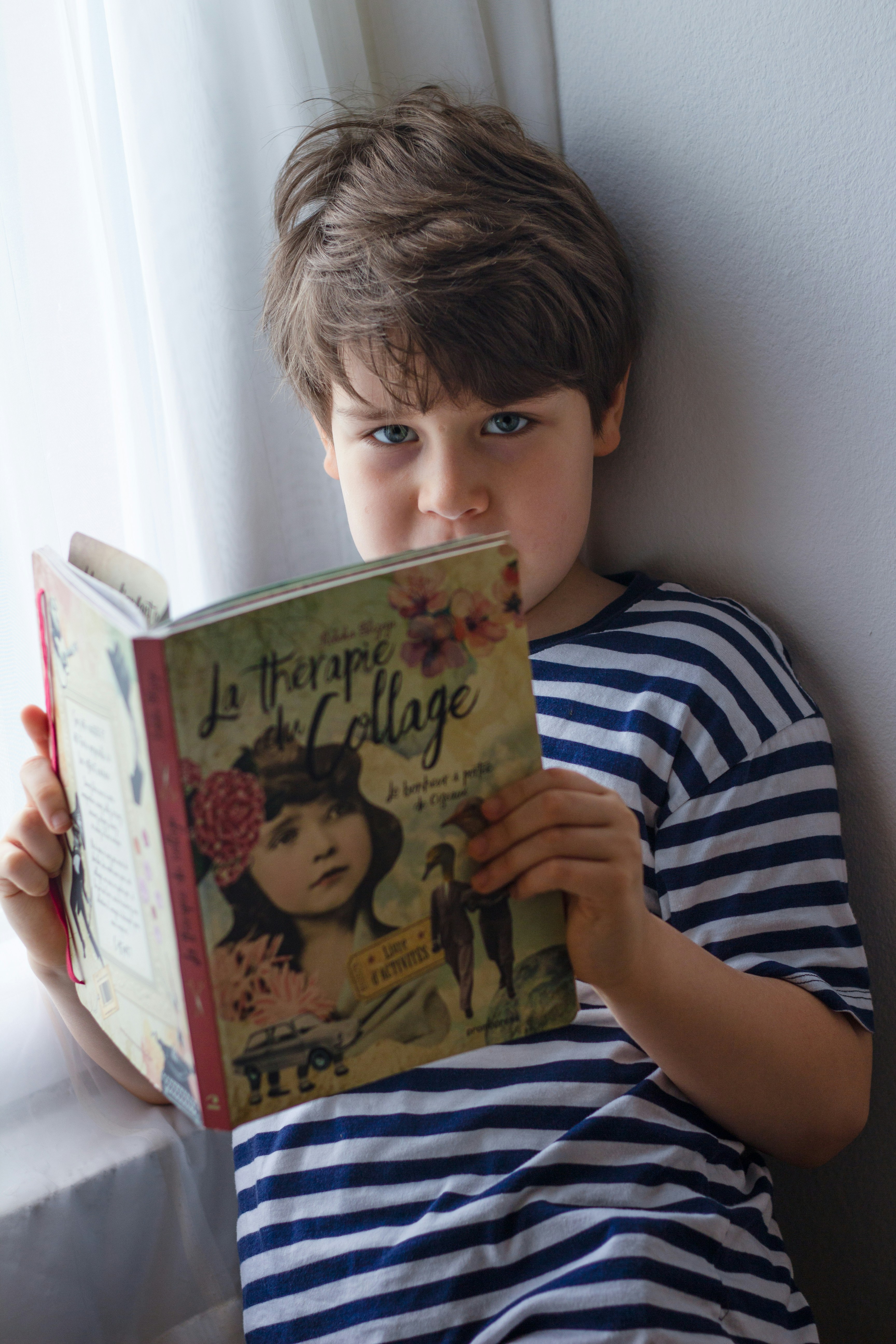 boy in black and white stripe shirt reading book