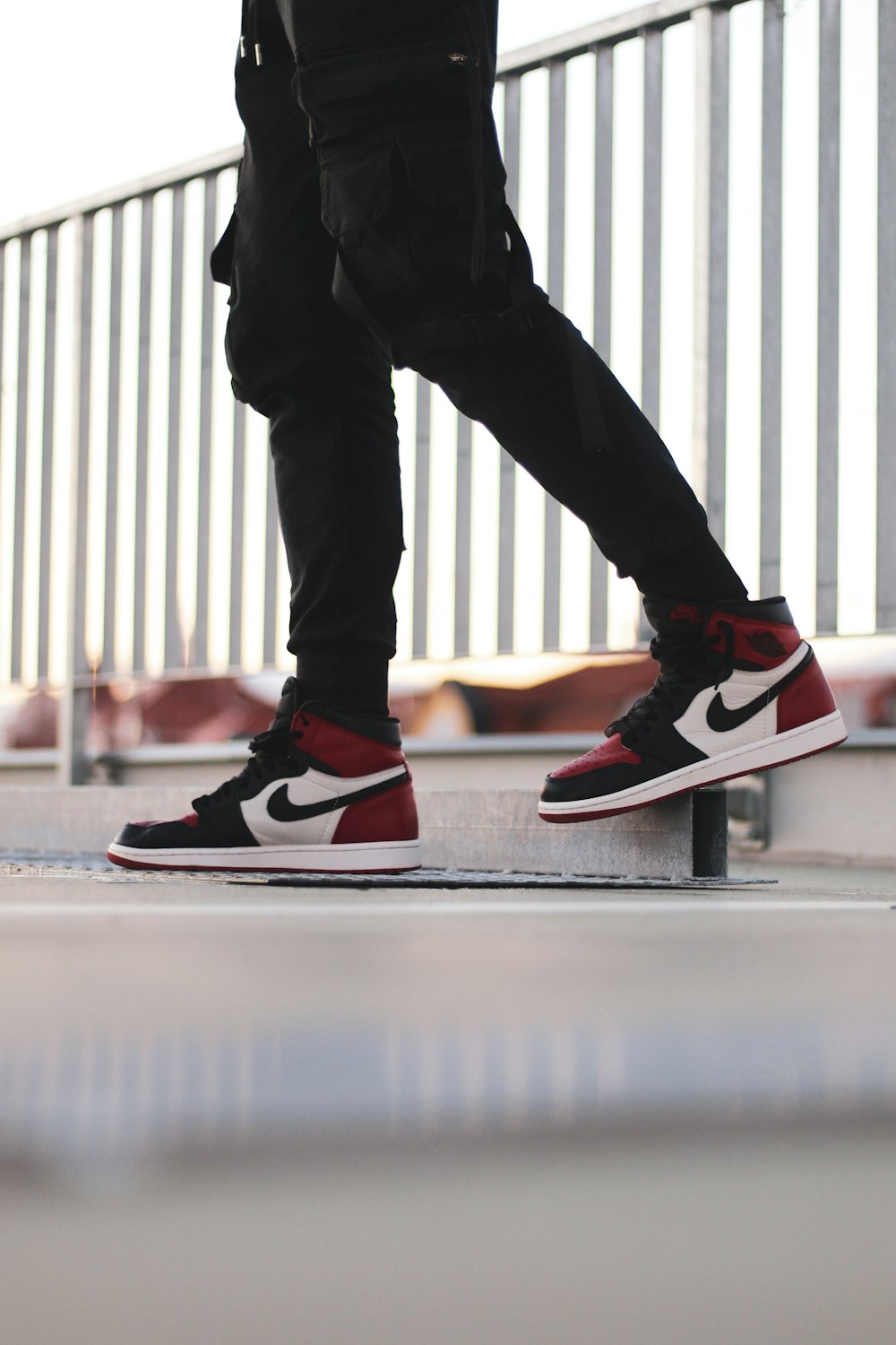 Persona in pantaloni neri e scarpe da ginnastica Nike rosse e bianche