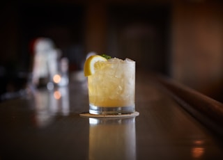 clear drinking glass with yellow liquid and sliced lemon