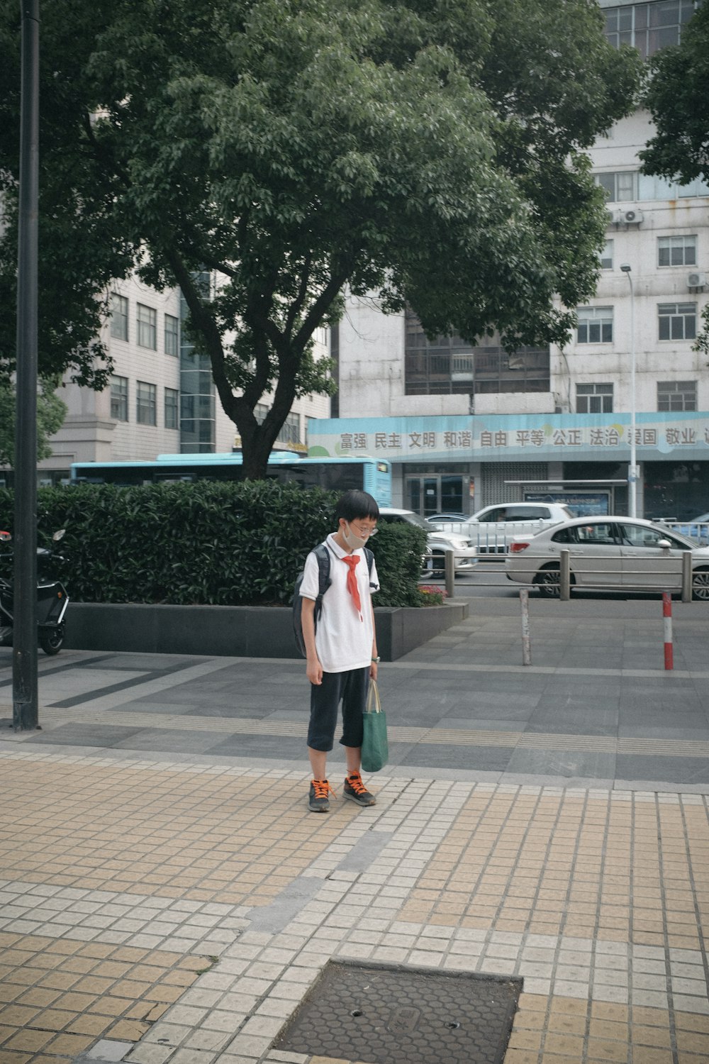 donna in camicia bianca a maniche lunghe in piedi sul marciapiede durante il giorno