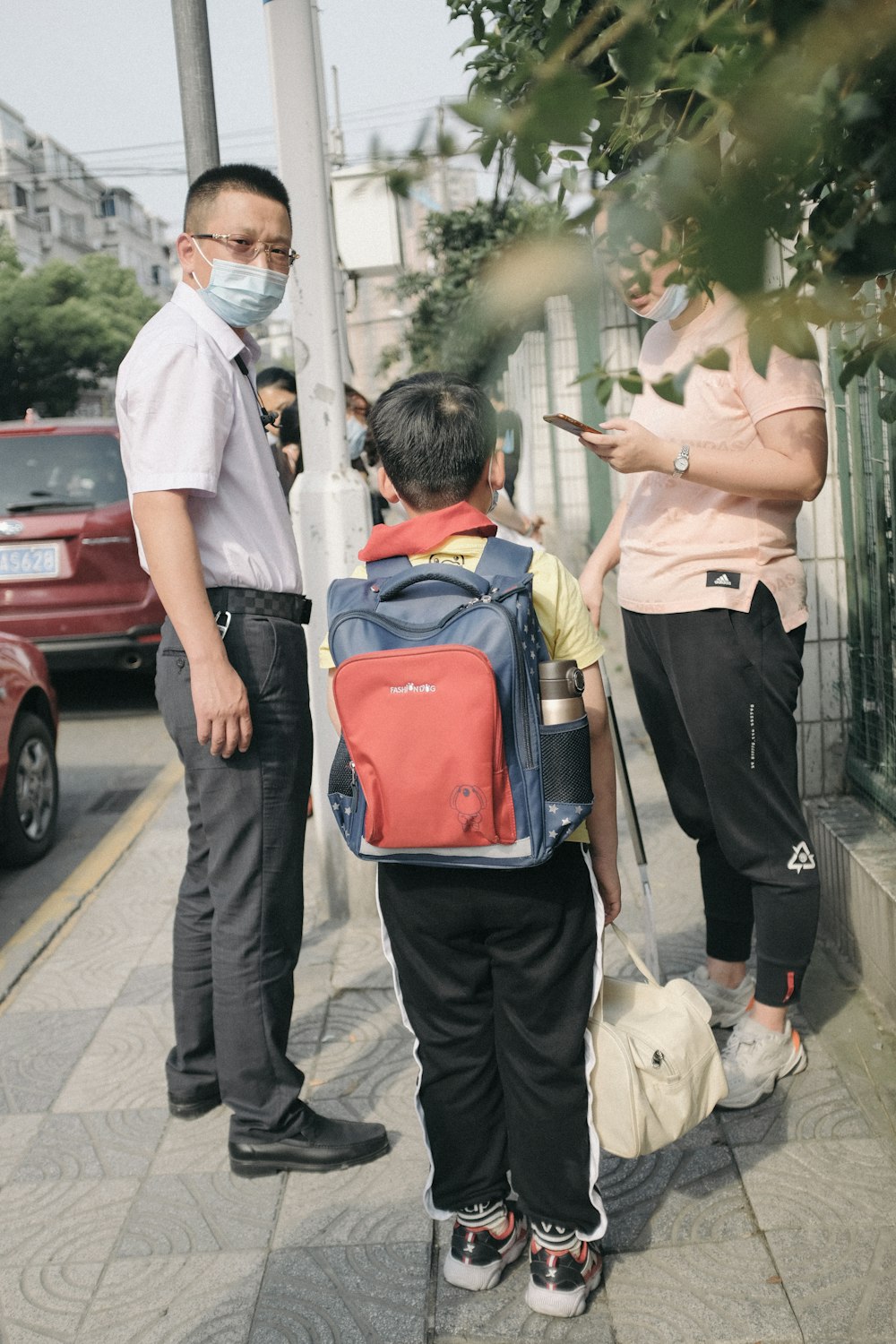 man in white t-shirt and black pants holding red and black backpack