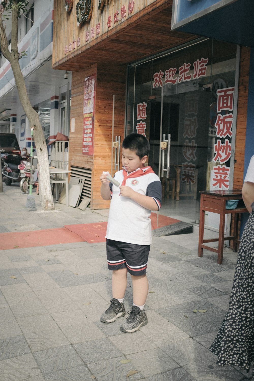 boy in white crew neck t-shirt and black shorts holding white and red plastic toy