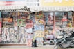 A storefront packed with an assortment of colorful toys, including action figures, toy cars, and various playsets, is displayed prominently. The shelves are stacked high with boxed toys and accessories, creating a vibrant and busy scene. A scooter is parked in front of the shop, adding to the bustling urban setting.