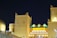 A Moroccan-themed building is illuminated at night with bright yellow lighting on traditional architecture featuring crenelated walls and towers. A prominent sign displaying the word 'MOROCCO' in bold yellow letters is visible.