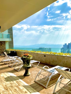 Rooftop terrace with lounge seating and panoramic view of Rio skyline.