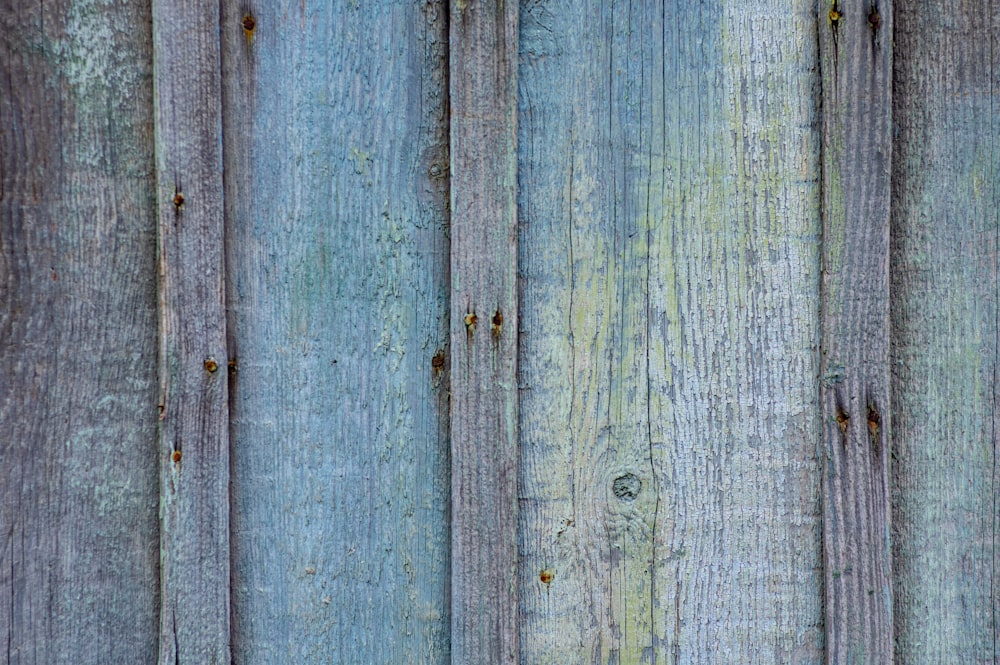 a close up of a wooden fence with blue paint