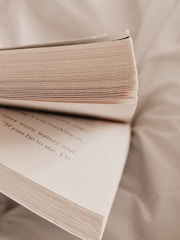 Close-up of an open book with a warm light highlighting the printed pages.