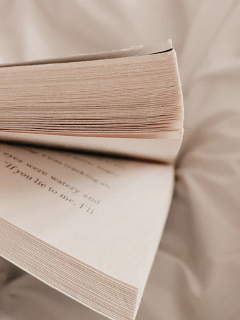 Close-up of an open book with soft lighting highlighting the pages in a cozy library corner.