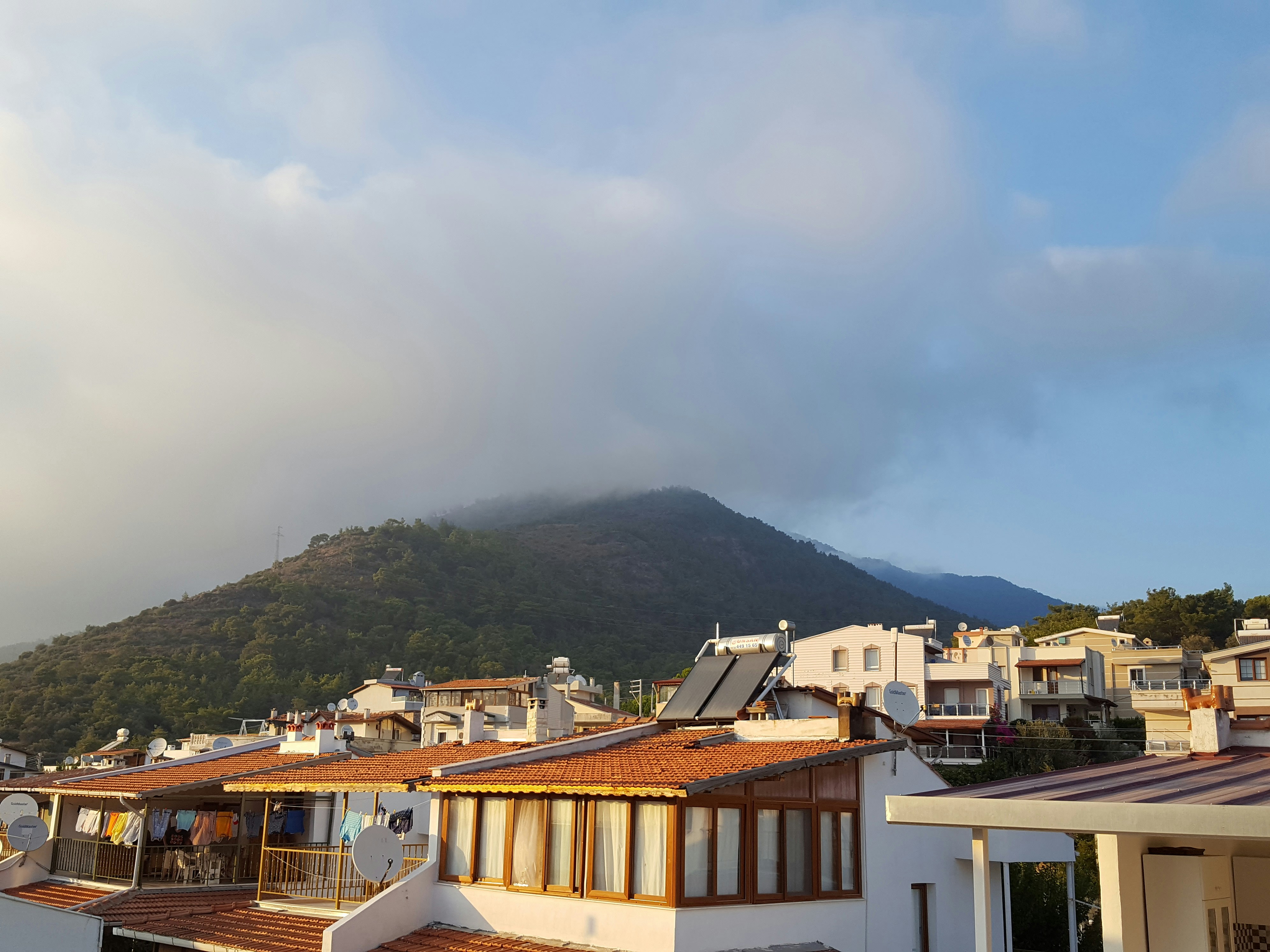 white and brown concrete house near green mountain under white clouds during daytime, This is my 2019 summer view 2</p><p>#summer #beach #sun #sand #sunny #vacation #view #houses #mountain