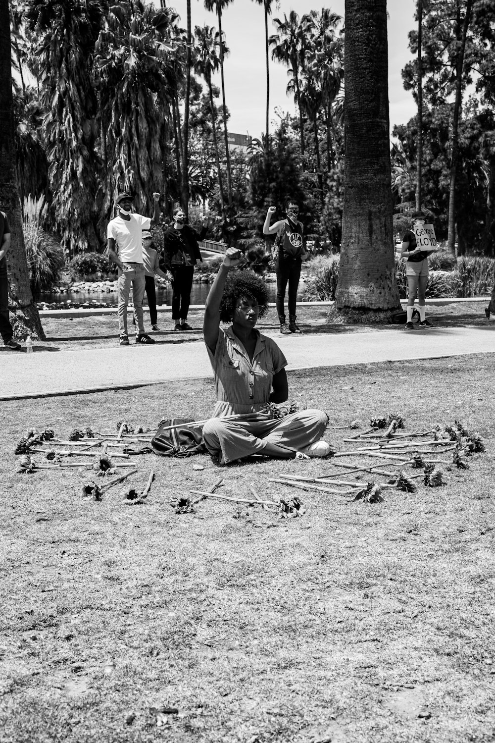 grayscale photo of woman sitting on ground with dried leaves