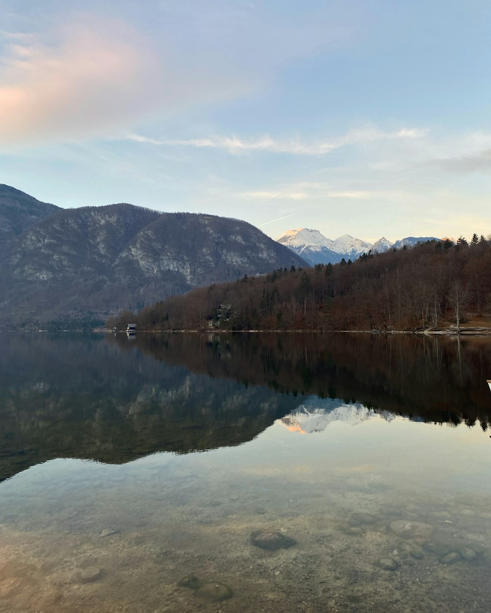 lake near green trees and mountain under white clouds and blue sky during daytime