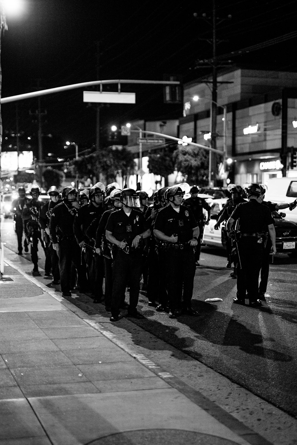 grayscale photo of people in black suits walking on street