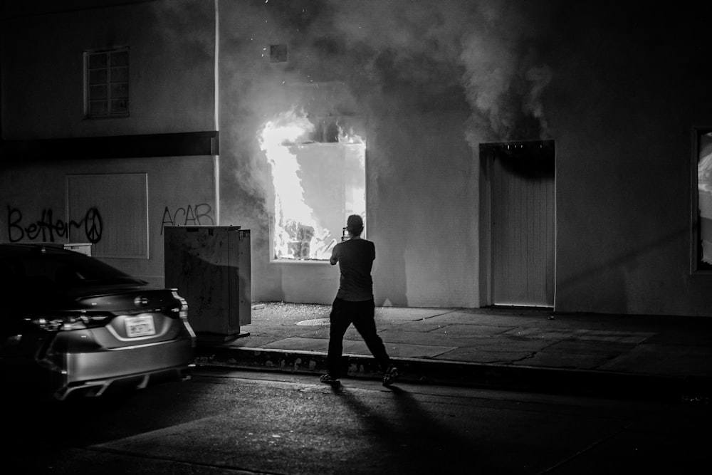 man in black jacket standing in front of white car