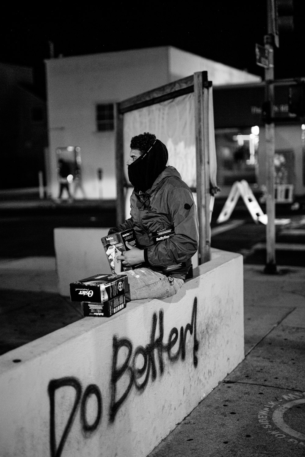 man in brown jacket and black knit cap sitting on concrete bench