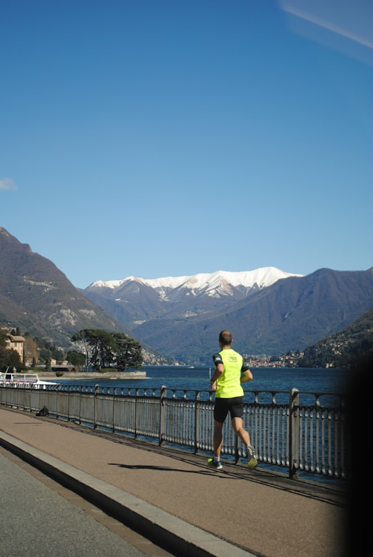 woman in yellow shirt standing on bridge during daytime in Lake Como Italy