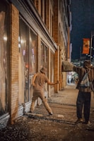 A tense standoff between two survivors in a ruined urban street at dusk