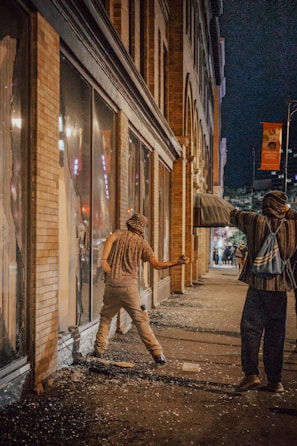 A tense standoff between two survivors in a ruined urban street at dusk
