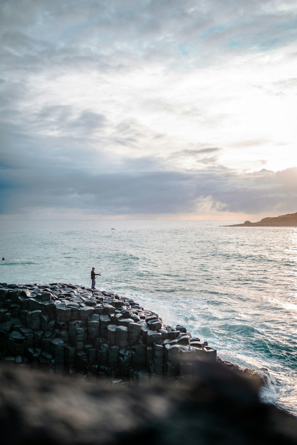 person standing on gray rock formation near body of water during daytime