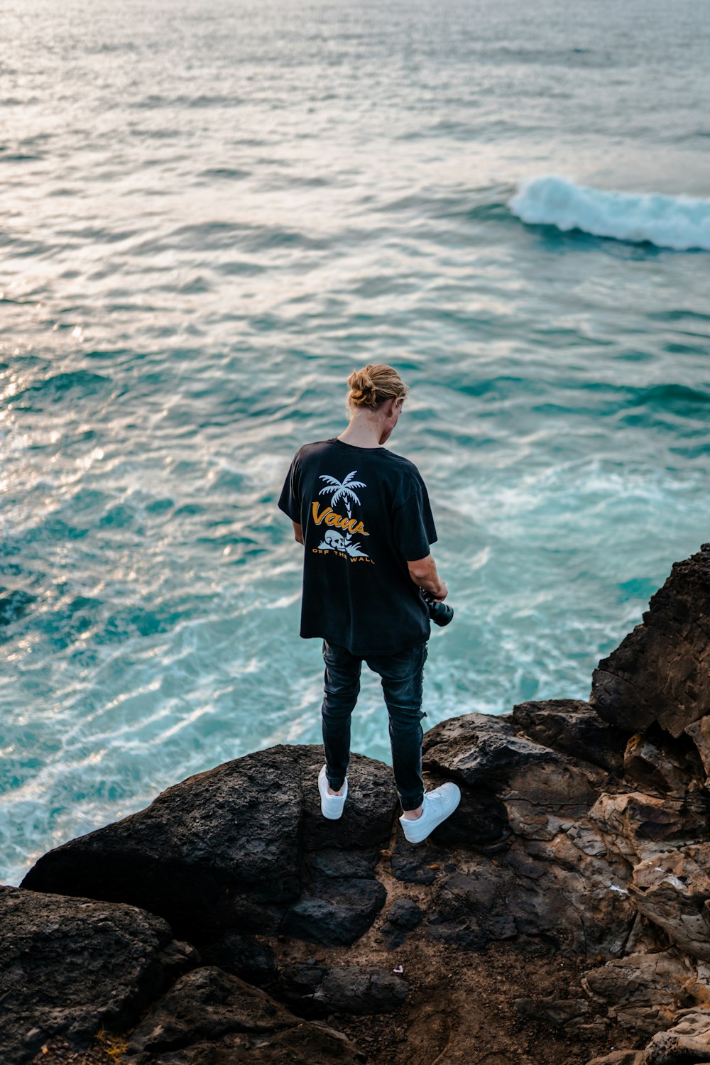 uma pessoa de pé em uma rocha olhando para o oceano