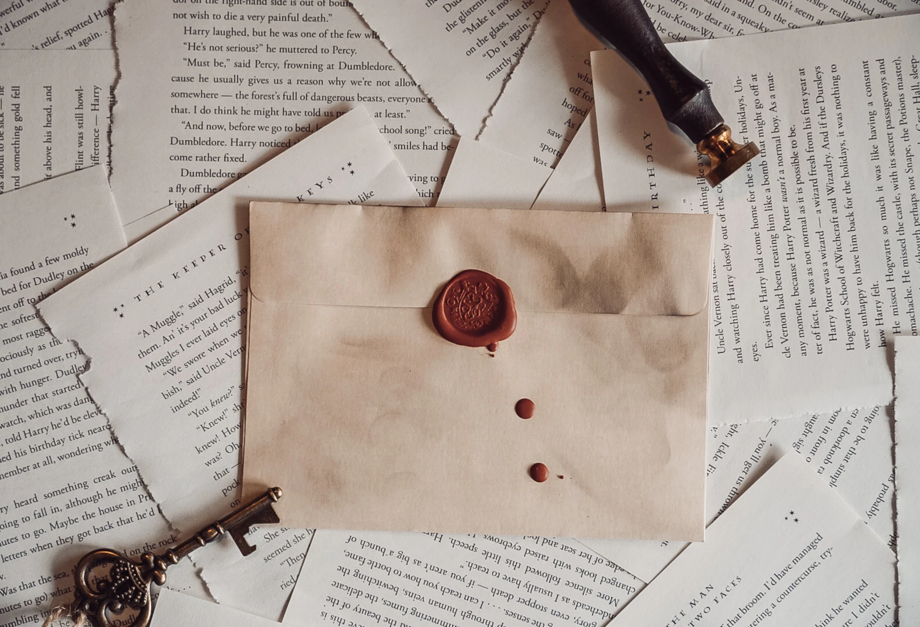 A kraft envelope with a red wax seal and stray drips, lying on loose book pages